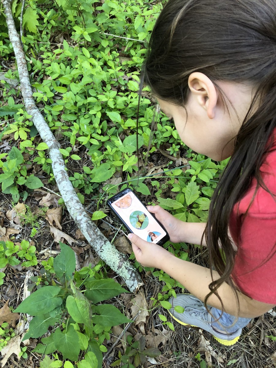 A girl uses a Kids in Parks e-activity to learn about flora on a trail