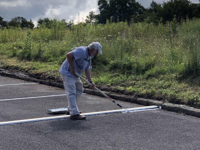 A volunteer stripes the parking lot with paint at The Bluffs Restaurant
