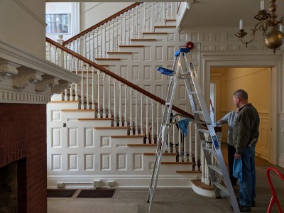NPS staff clean the woodwork on the stairway at Flat Top Manor at Moses H. Cone Memorial Park.