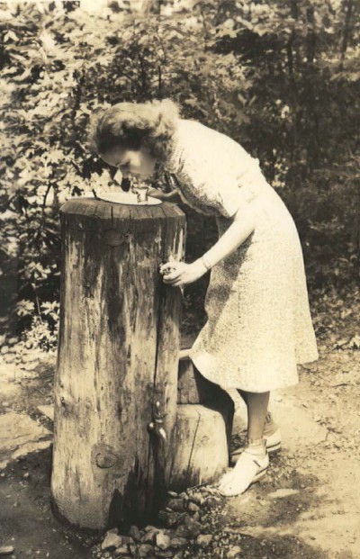 A woman drinks from a log water fountain in 1940 at Cumberland Knob, the first recreation area along the Blue Ridge Parkway.